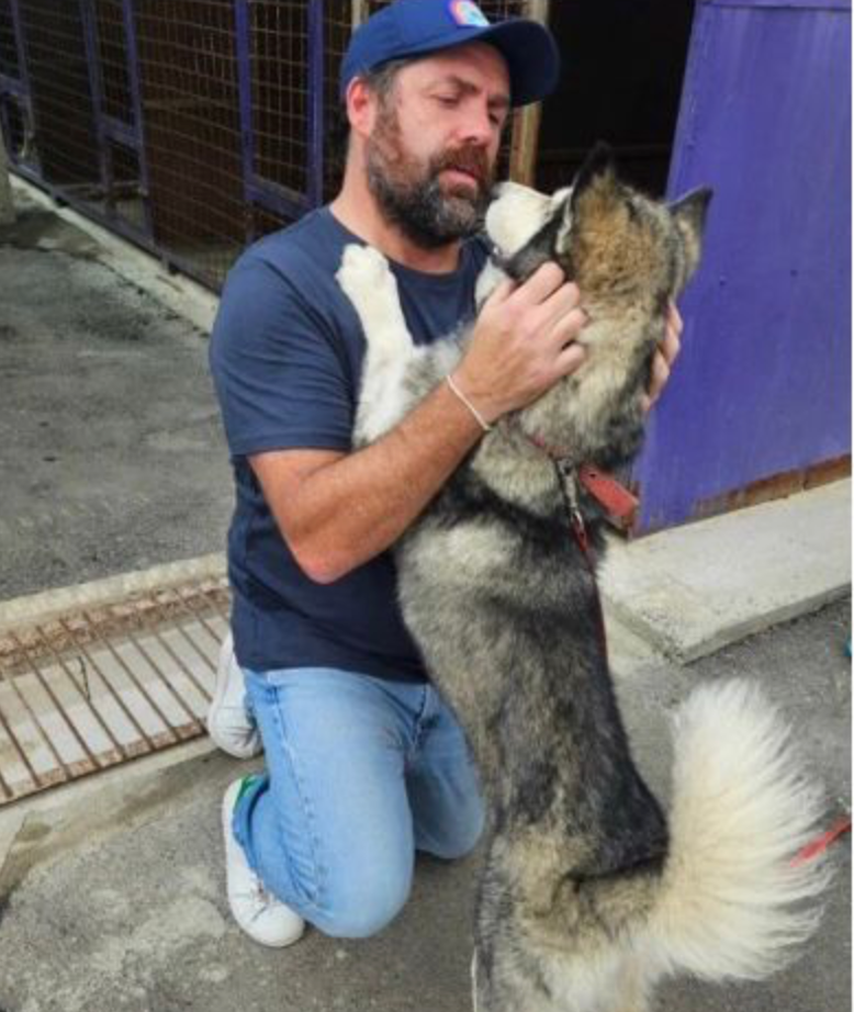 Brian Rutter kneeling with a dog outdoors.