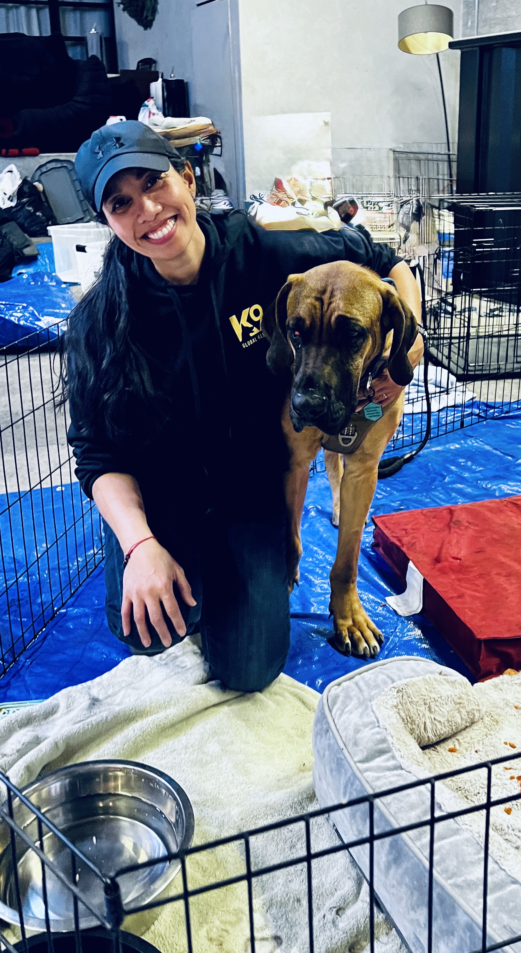 Christina Irinco kneeling beside a dog in a rescue support area.